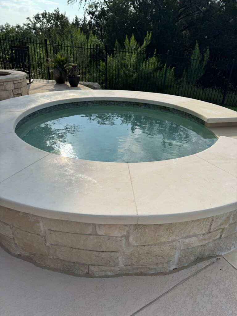 A close-up of a completed hot tub with stone siding and coping by 5 Daughters Total Outdoors in Austin, TX.