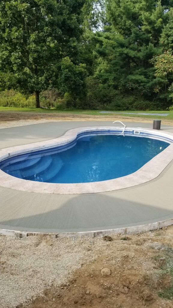 A completed inground pool with built-in steps and concrete decking, showcasing work by My Pool Guys of Erie, PA.
