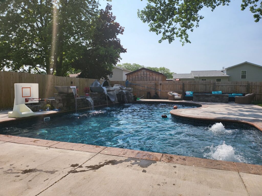 A completed inground pool featuring waterfalls and a basketball hoop, installed by My Pool Guys of Erie, PA.