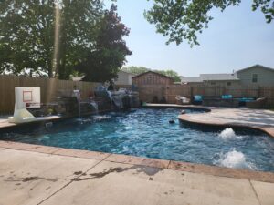 A completed inground pool featuring waterfalls and a basketball hoop, installed by My Pool Guys of Erie, PA.