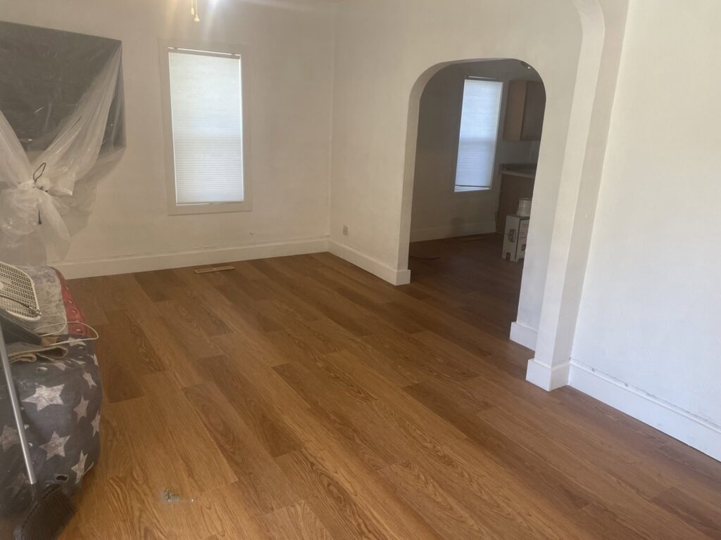 A bright interior room with newly installed laminate flooring and freshly painted white walls by Knutson's Property Maintenance Llc in Williston, ND.