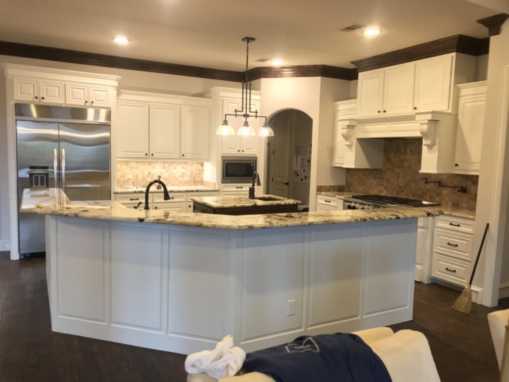 A beautifully completed kitchen remodel with new white cabinets, granite countertops, and backsplash by Finesse Painting and Remodeling in Fort Worth, TX.