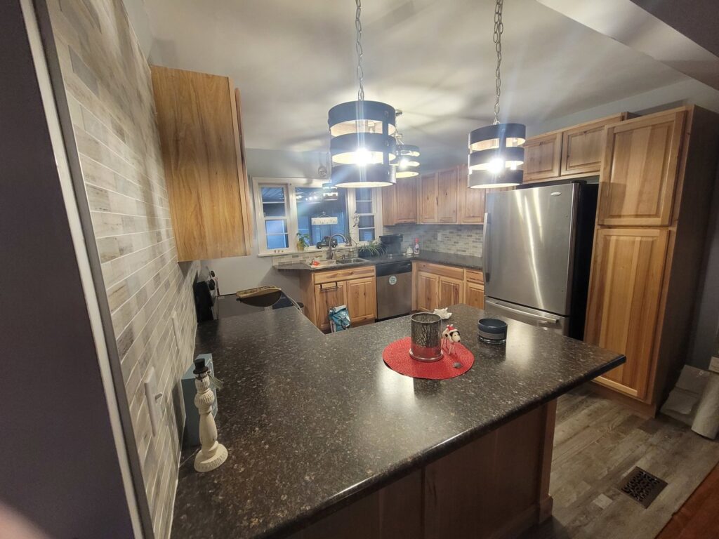 A beautifully completed kitchen remodel featuring light wood cabinets and modern pendant lights by Ben Nye The Fix-It Guy in Erie, PA.