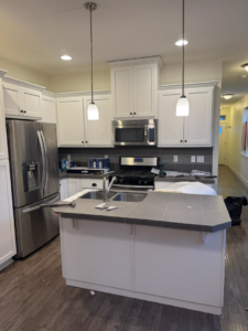 Newly completed white kitchen remodel with stainless steel appliances and island by Restore Renew Remodel in Portland, OR.