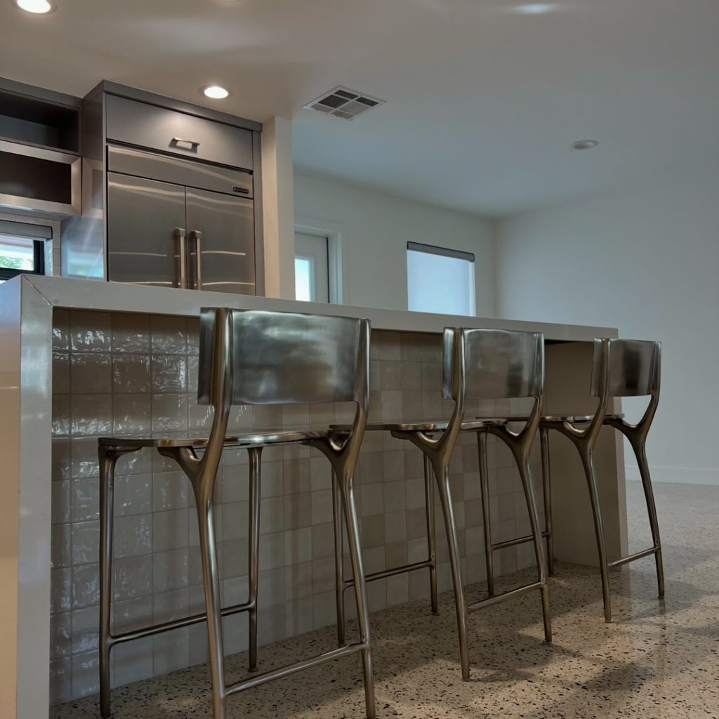 A beautifully completed kitchen remodel featuring a tiled island and stainless steel appliances by Broward Tile Guys in Pompano Beach, FL.