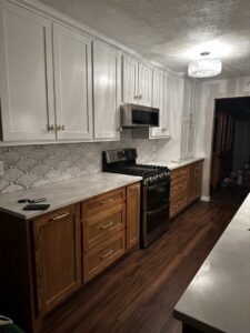 A completed kitchen remodel featuring white upper cabinets, wood lower cabinets, and a new backsplash by Ricos Renovations in Arlington, TX