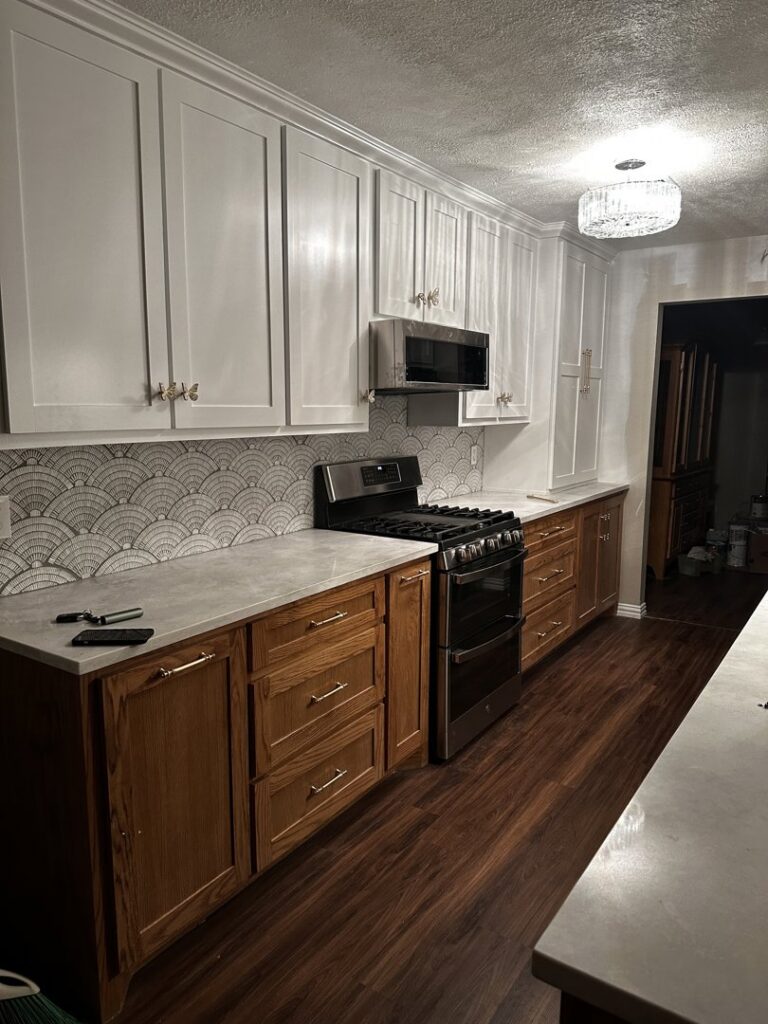 A completed kitchen remodel featuring white upper cabinets, wood lower cabinets, and a new backsplash by Ricos Renovations in Arlington, TX