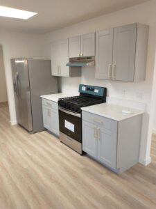 A newly renovated kitchen with grey cabinets and stainless steel appliances by San Marcos Drywall and Paint in Austin, TX