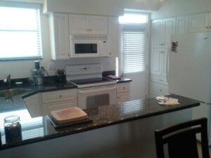 A completed kitchen renovation with white cabinets and dark countertops by Corley Construction Inc in Fort Lauderdale, FL