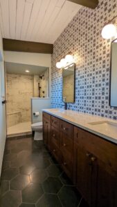A completed modern bathroom renovation featuring a new vanity, shower, and patterned wallpaper by The Foundation Guys in Lakewood, CO
