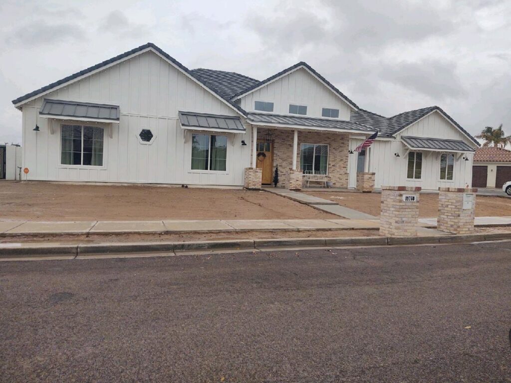 A completed modern farmhouse style home with white siding and stone accents by AZ Framing and Remodeling in Peoria, AZ