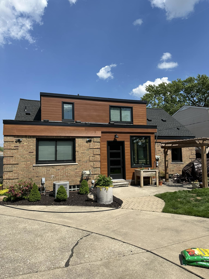 A beautifully completed modern house exterior with brick and wood siding by New Life Custom Carpentry in Livonia, MI.