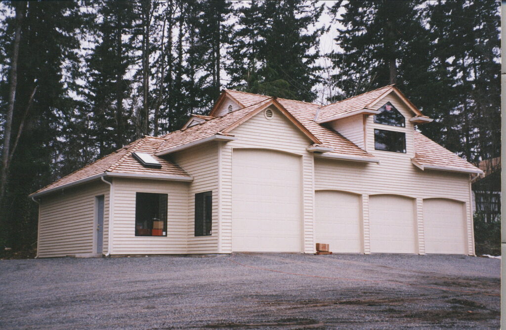 A large, newly built garage with multiple doors and a cedar shake roof by Garages Etc in Tacoma, WA