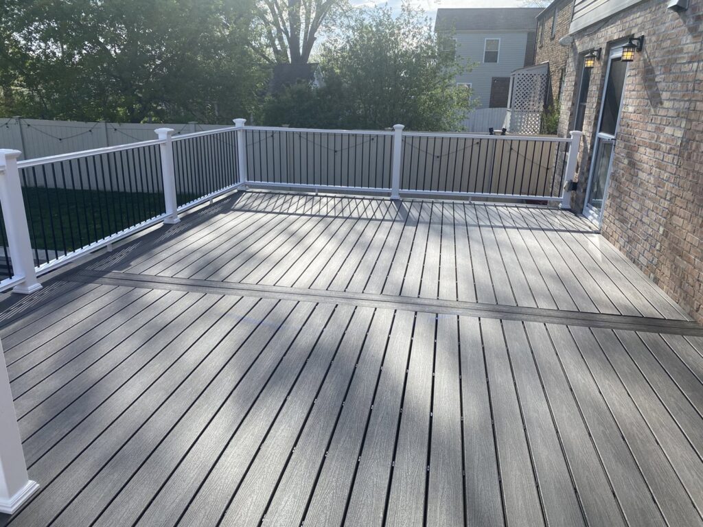 A newly completed outdoor deck with composite decking and white railings, built by Keeler Construction Group Inc. in Blue Island, IL.