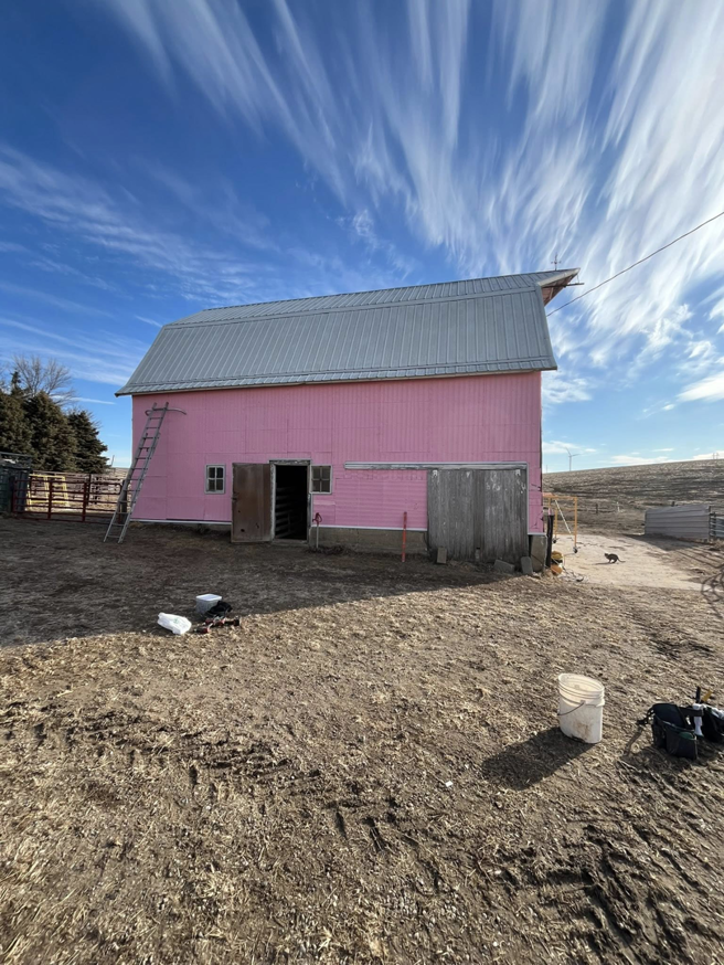 A completed pink barn with new metal roofing and exterior painting by CJP Construction handyman services in Pierce, NE.