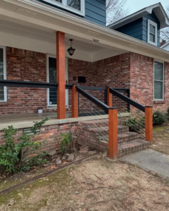 A newly installed porch railing system with wooden posts and cable infill by PODavis Home Helpers in Little Rock, AR