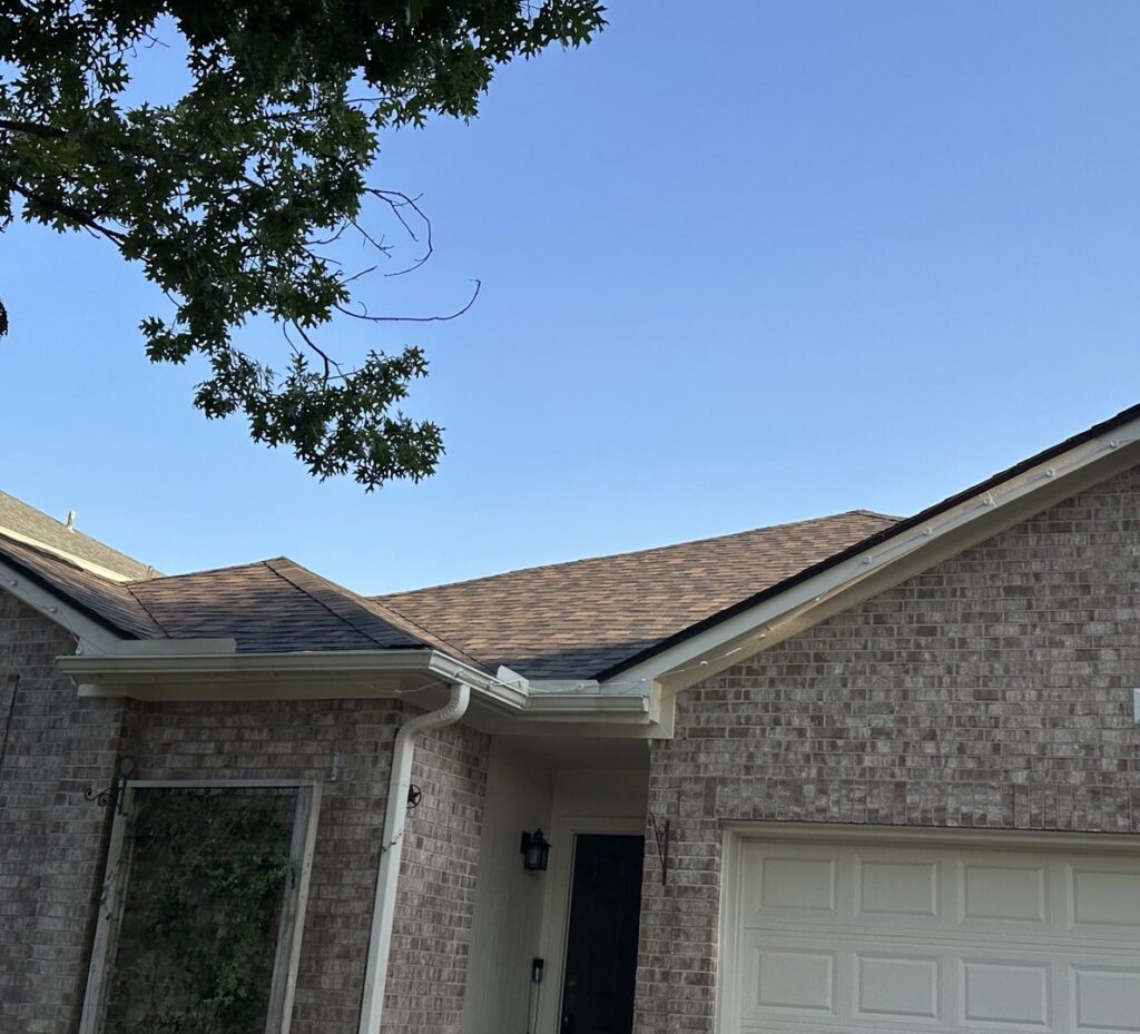 A residential house with a newly completed brown shingle roof and white gutters, showcasing work by APEX Roofing in Georgetown, TX.