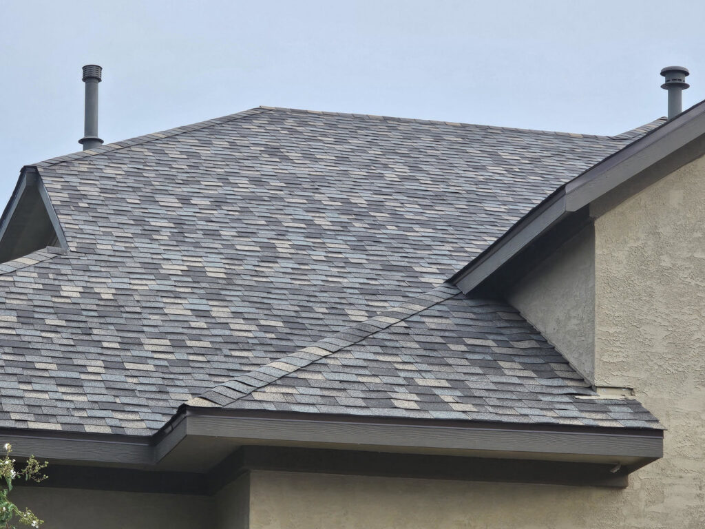 A close-up of a newly completed residential roof with multi-colored shingles and vents, showcasing work by APEX Roofing in Georgetown, TX.
