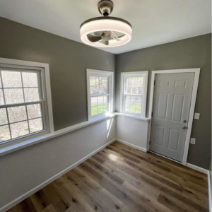 A completed room makeover featuring new flooring, painted walls, a new door, and a ceiling fan by A 2 Z Home Services - Fairmont WV.