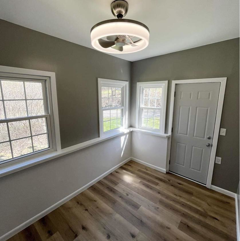 A completed room makeover featuring new flooring, painted walls, a new door, and a ceiling fan by A 2 Z Home Services - Fairmont WV.