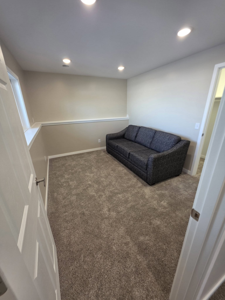 A completed room remodel with new carpet, painted walls, and a sofa by Rosenthal Remodeling in Milton, WI.