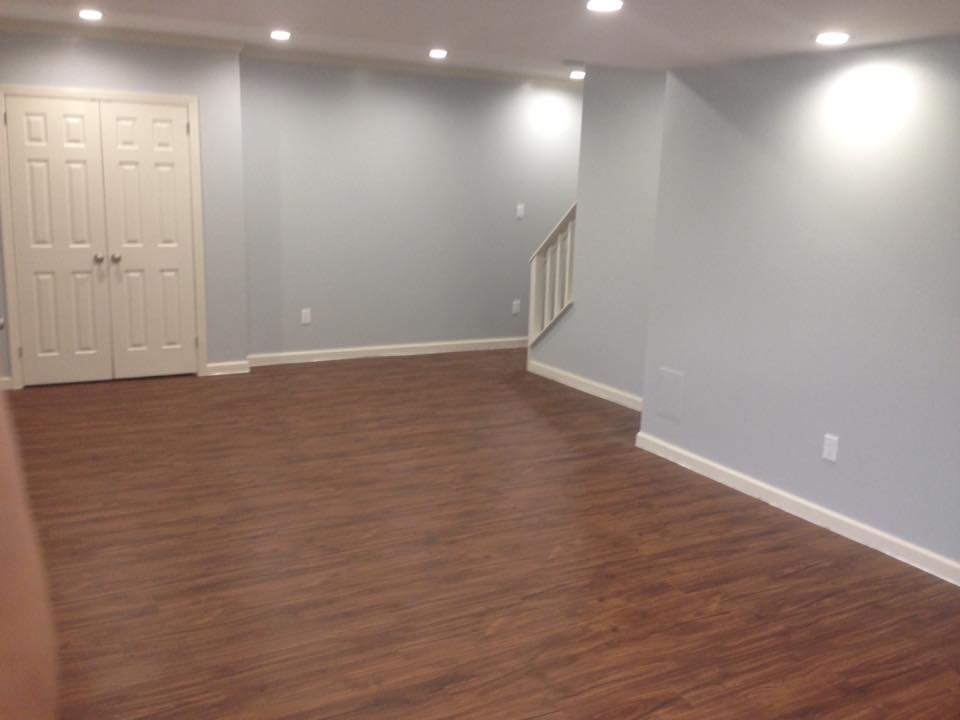A completed room renovation showcasing new hardwood flooring, recessed lighting, and painted walls by J Development in Pittsburgh, PA.