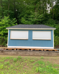 A newly completed blue shed-like structure with a dark roof and white windows, built by Yellow Ladder Contracting in Mount Pleasant, SC