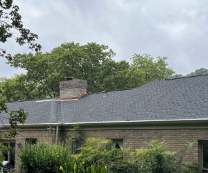 A beautifully completed dark shingle roof with a brick chimney, installed by Music City Exteriors in Nashville, TN