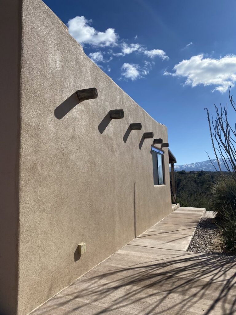 A beautifully completed stucco wall with decorative wooden beams by Old Pueblo Stucco, Inc. in Tucson, AZ