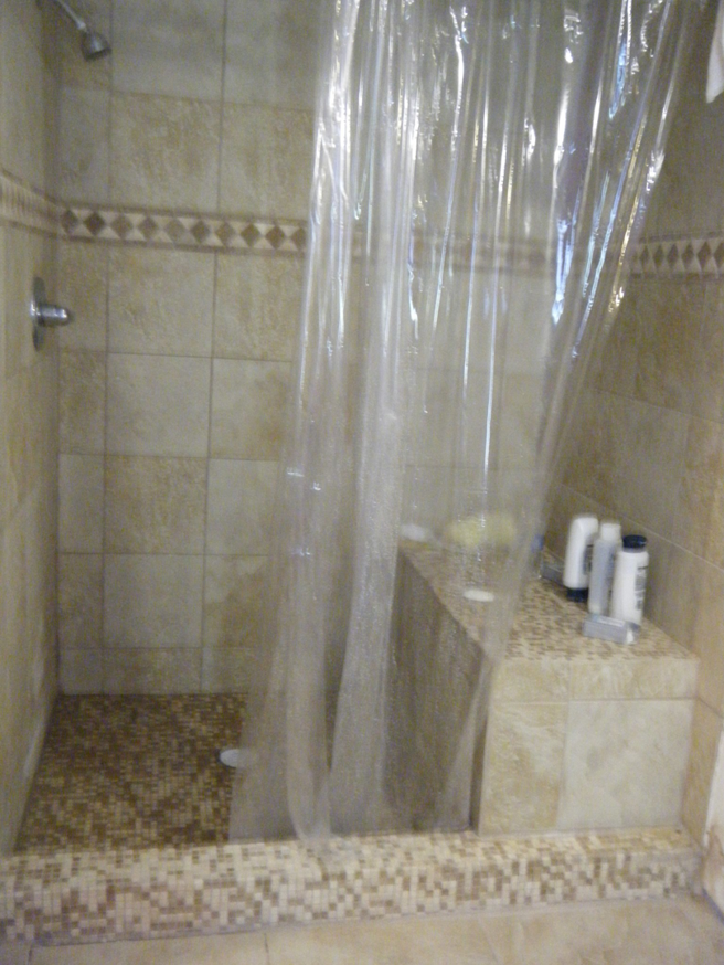 Completed tiled shower installation with a curtain and bench by Castillo Construction Company in Malden, MA