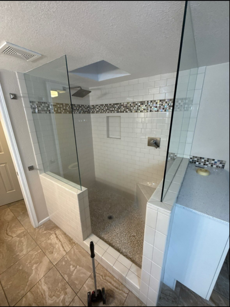 A newly completed tiled shower installation with a glass enclosure by Orange Door Custom Coatings in Phoenix, AZ.