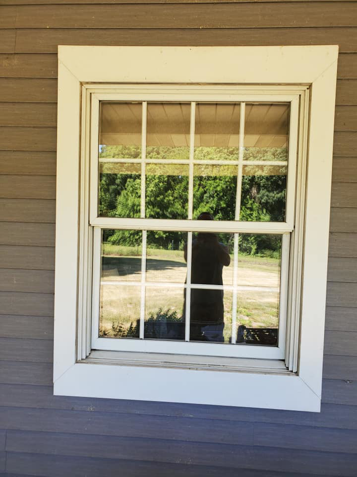 A completed window replacement with white grid and trim on a house exterior by Hack's Construction & Window Co in Fishers, IN