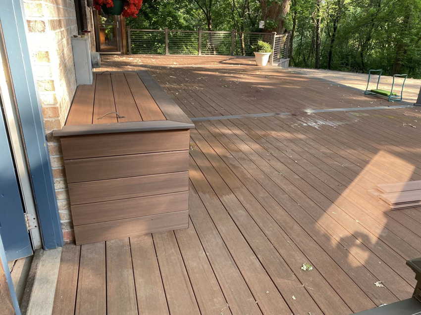 A spacious, newly completed wooden deck with a built-in storage bench, constructed by Building Arts by Jimmy Z in Cassville, WI.