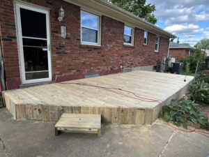 A newly completed wooden deck with a small step leading to the yard, built by A2 Construction in Louisville, KY.