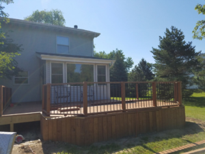 A newly completed wooden deck with railings in a backyard, built by Screwheads Decking And Supply Store in Racine, WI