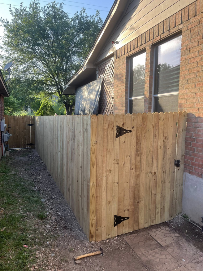 A completed wooden privacy fence with a gate, showcasing the general contracting services of Triple A' Construction in San Antonio, TX.