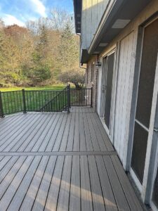 New composite deck installation with dark railings next to a house by APS Residential Services in Livonia, MI.