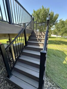 Durable composite deck stairs with sleek black metal railings, installed by Watertown Handyman in Watertown, SD.
