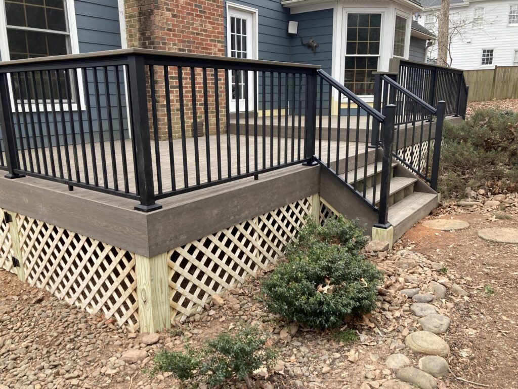 A newly installed composite deck featuring modern black metal railings and lattice skirting by Elite Xteriors NC in Cary, NC.