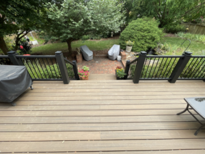 A modern composite deck with black railings overlooking a backyard patio, installed by Music City Home Experience in Nashville, TN.