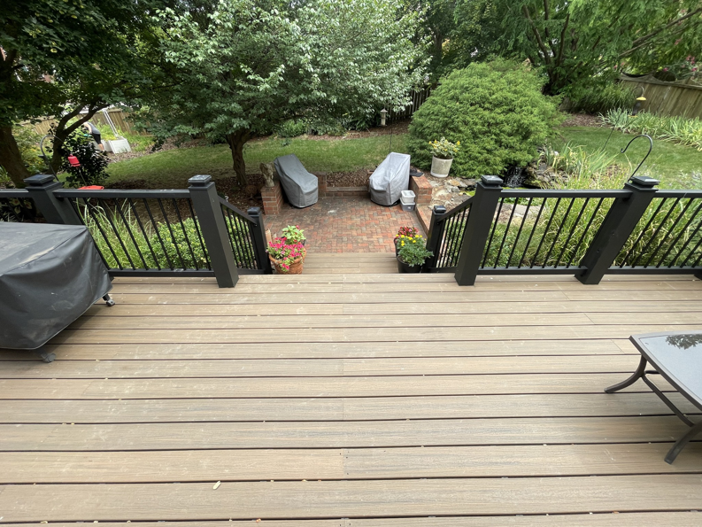 A modern composite deck with black railings overlooking a backyard patio, installed by Music City Home Experience in Nashville, TN.