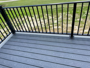 Close-up of new grey composite decking with modern black metal railings by Nailed It Custom Remodeling in Chesapeake, VA.