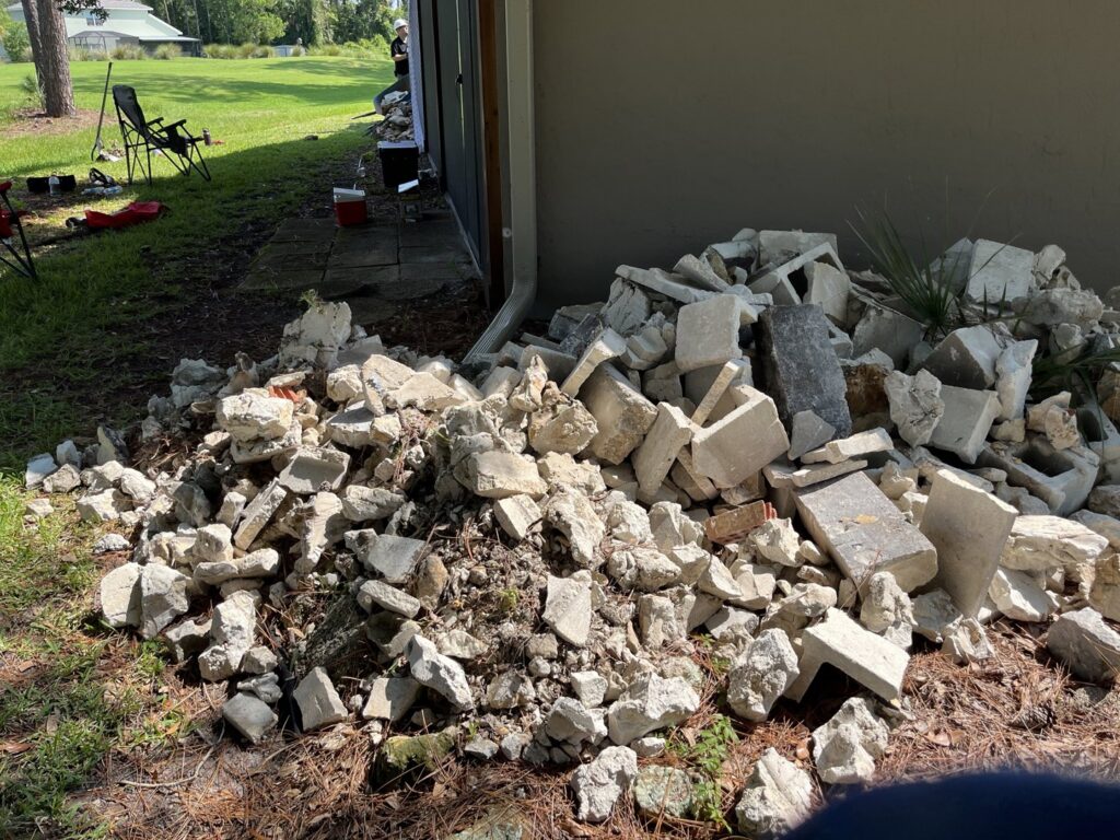 A pile of concrete and rock debris next to a residential building, ready for removal by DUMP 4 U Hauling in Jacksonville, FL.