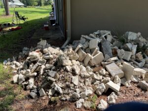 A pile of concrete and rock debris next to a residential building, ready for removal by DUMP 4 U Hauling in Jacksonville, FL.