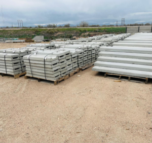 Stacks of precast concrete barriers and curbs stored on pallets at Arco Concrete Inc in Fort Lupton, CO