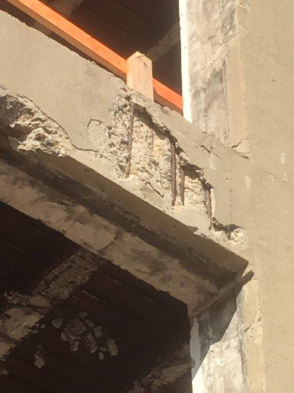 Close-up of a concrete beam showing exposed rebar and damage, indicating a structural repair by Kemna Restoration & Construction in Indianapolis, IN.
