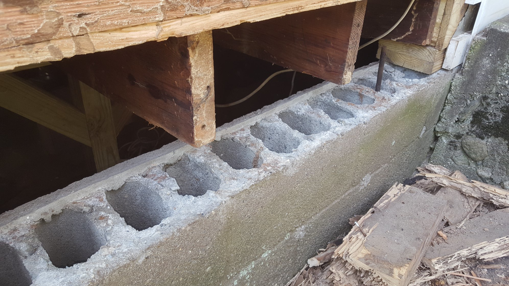 Close-up of a concrete block foundation and wooden joists during a repair project by DiBenedetto Building & Remodeling in Worcester, MA.