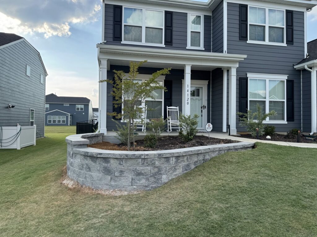 A newly constructed concrete block retaining wall in front of a modern home by Rodriguez Concrete Creations in Rock Hill, SC.