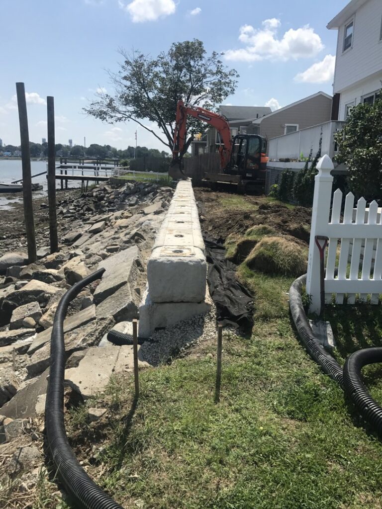 A concrete block retaining wall constructed along a waterfront by Solimini Excavation and Utility in Freetown, MA