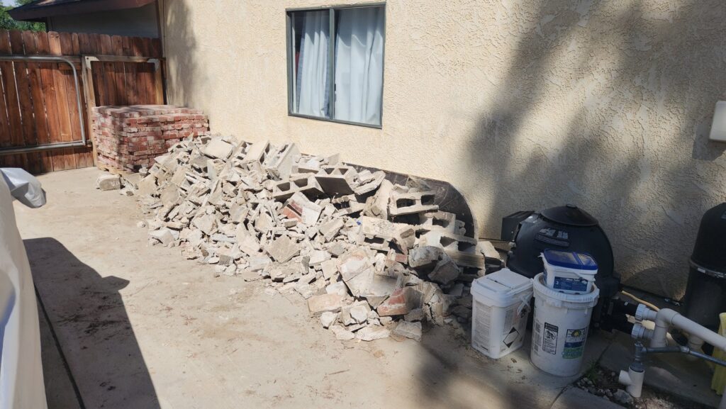 A pile of concrete blocks and construction debris next to a residential house, ready for removal by Bakersfield Roll-Off Service in Bakersfield, CA.